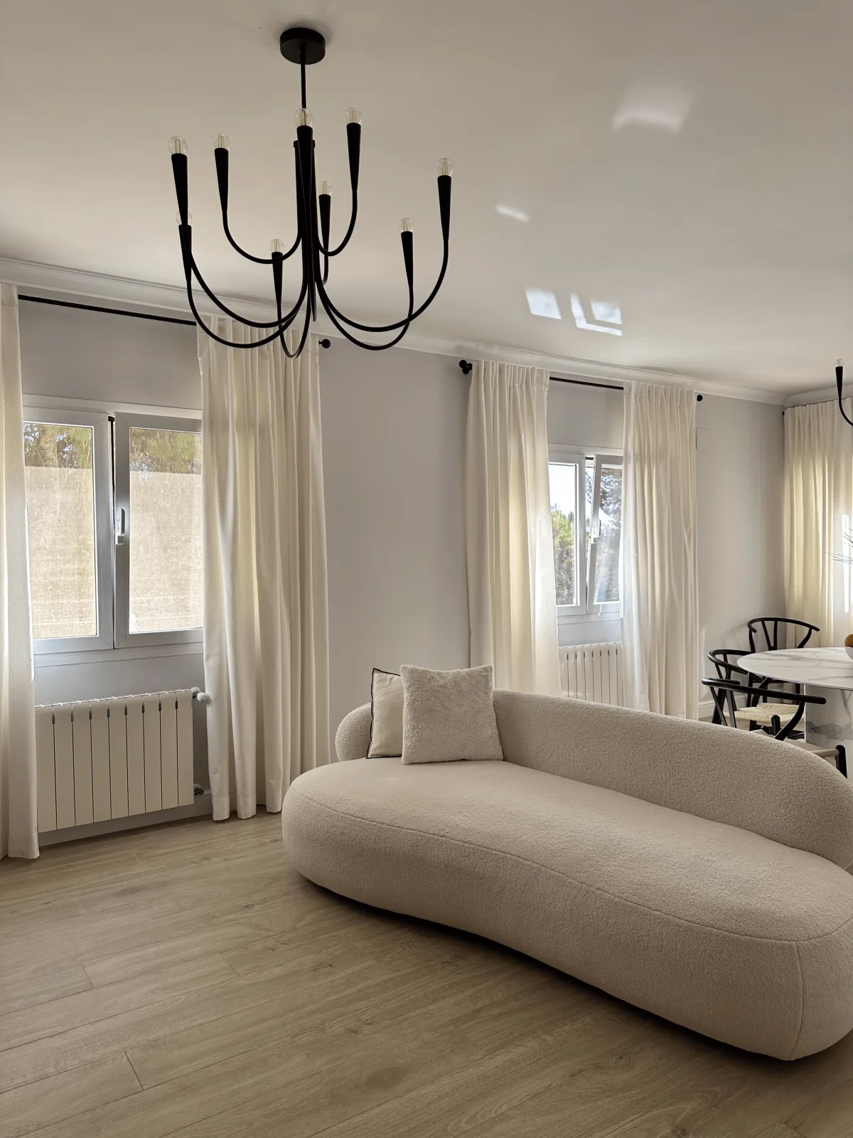 Salón con visillos a medida y sofá curvo de boucle