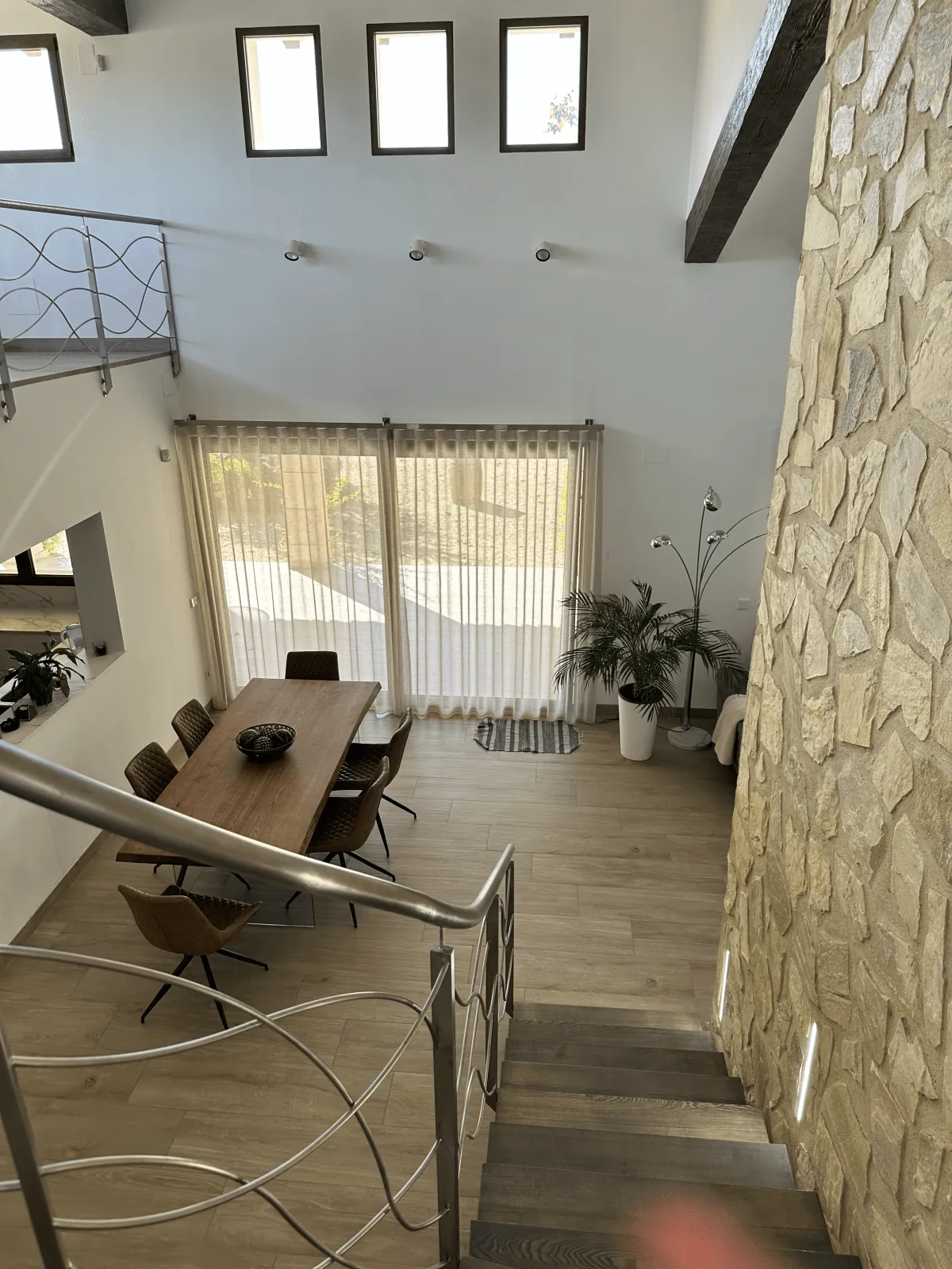 Zona de escalera con pared de piedra y visillo a medida