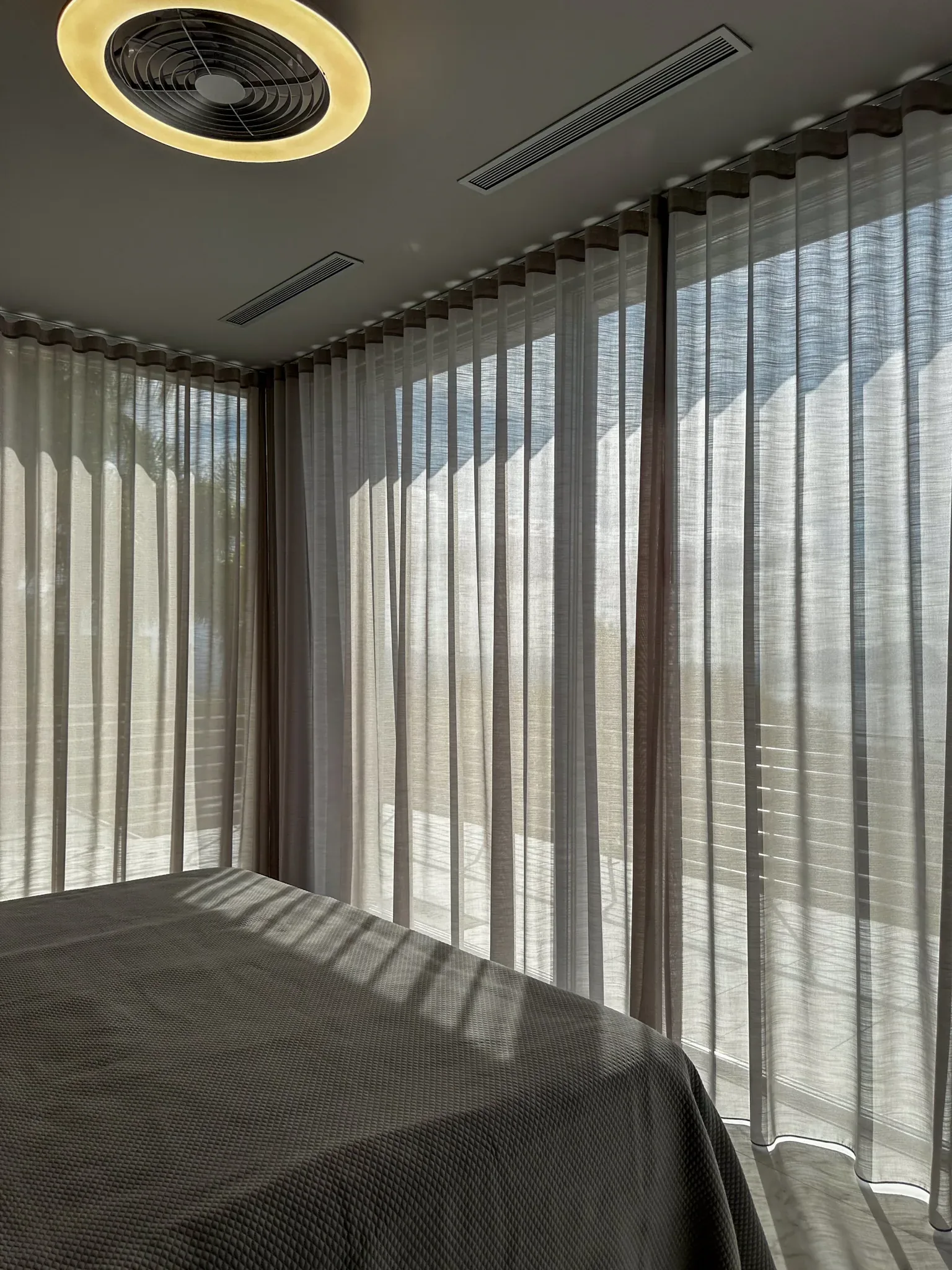 Detalle de la cortina y el estor a medida junto a la cama, en la misma villa con terraza y vistas al Mediterráneo