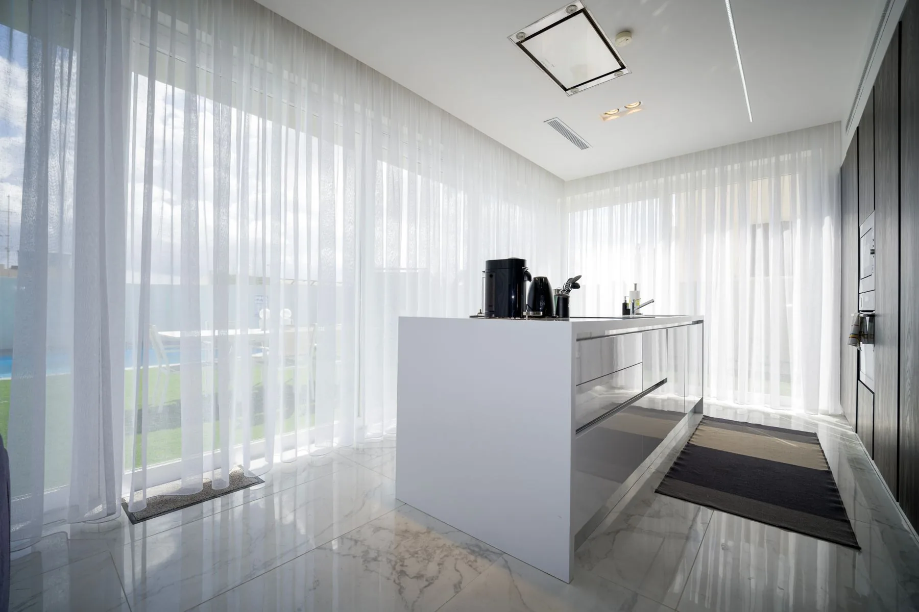Cocina de una villa con visillo junto al gran ventanal