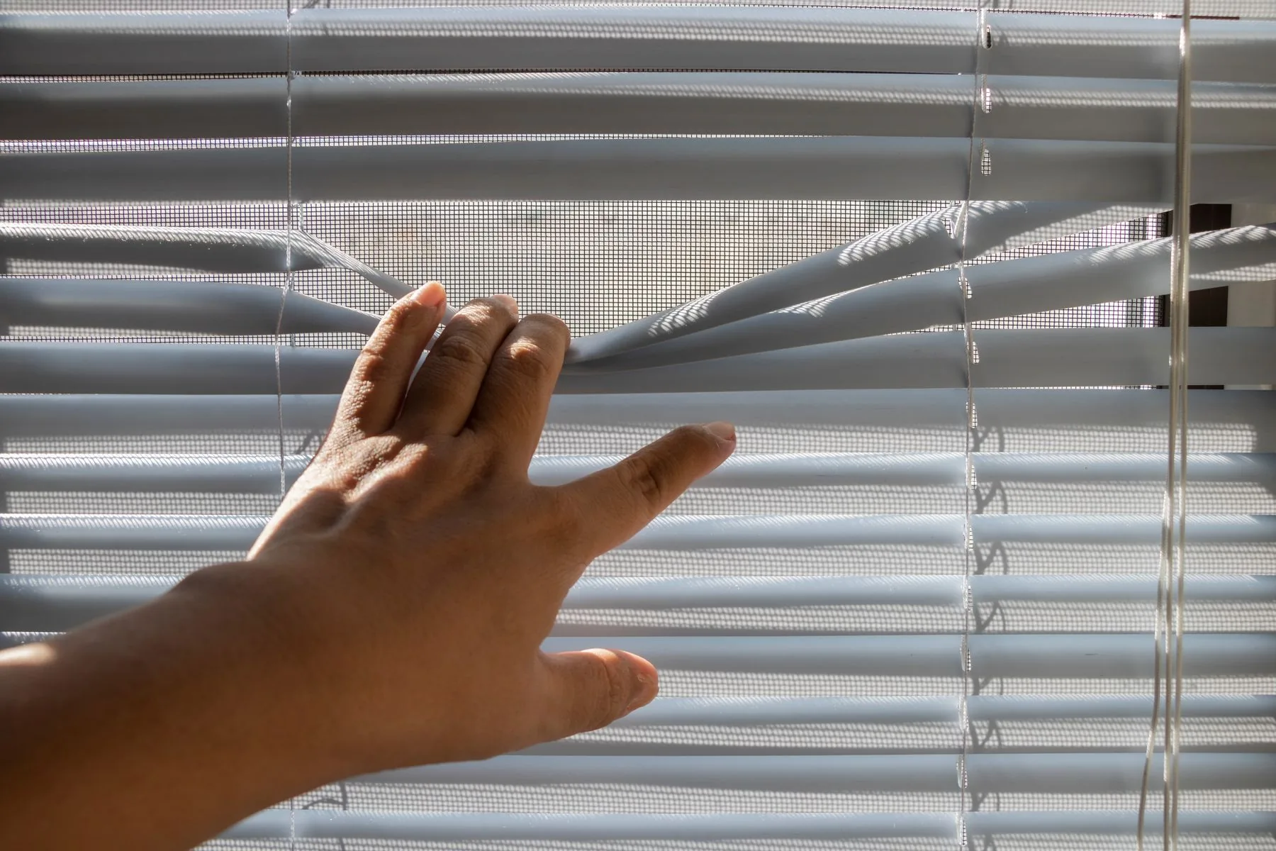 Mano abriendo un estor para dejar entrar la luz