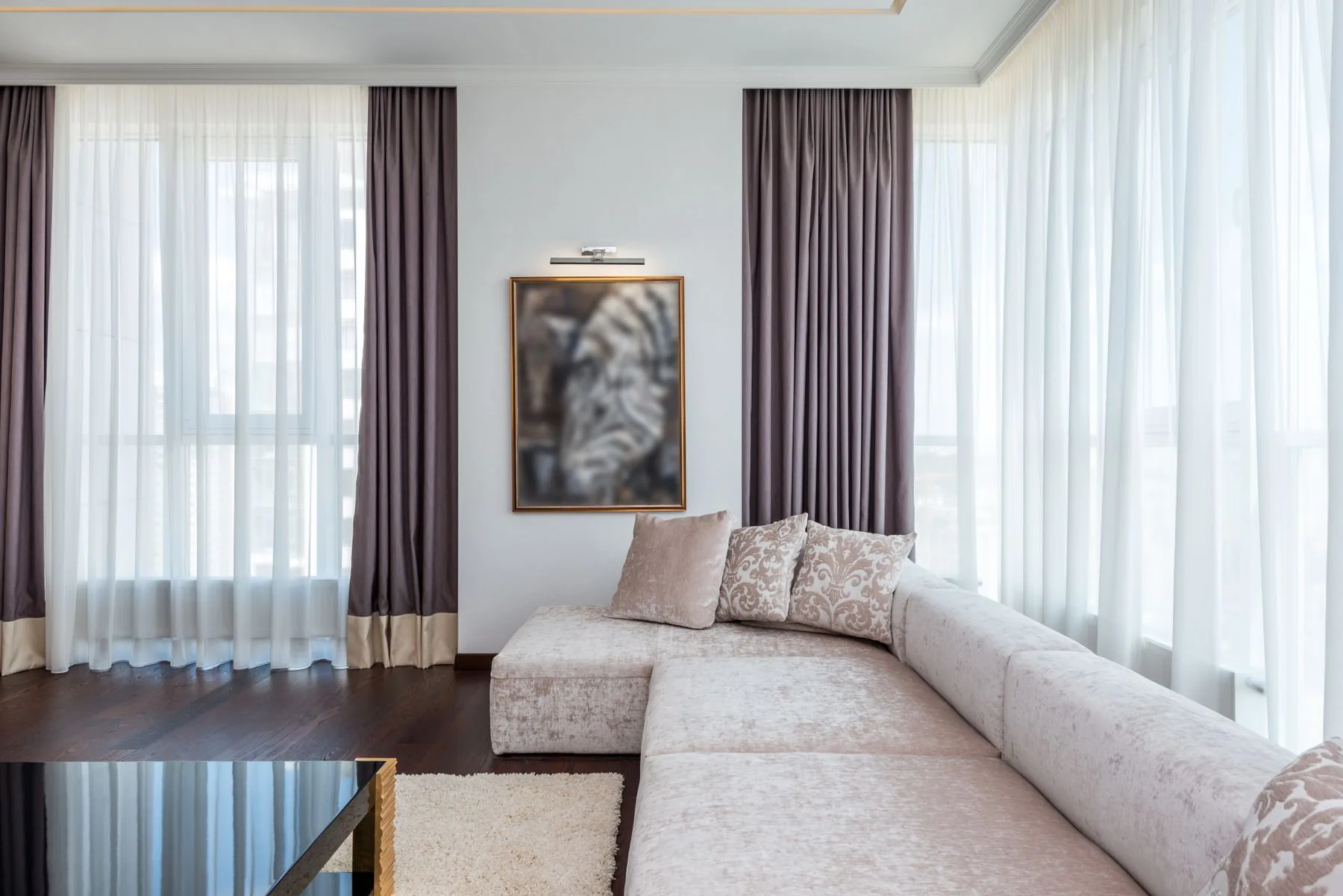 Salón moderno con sofá y cortinas junto a un gran ventanal