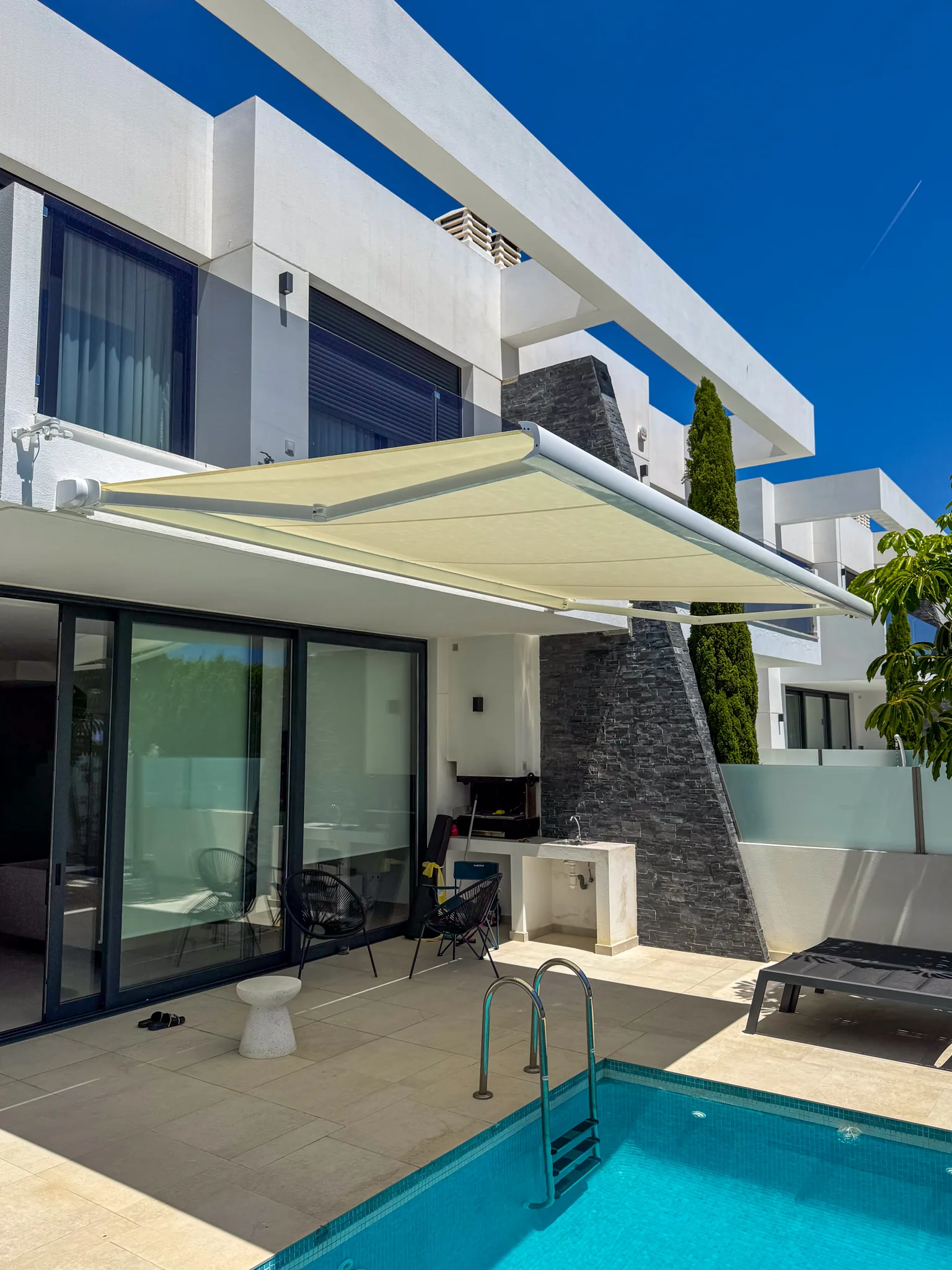 Toldo instalado en la terraza de una villa con piscina