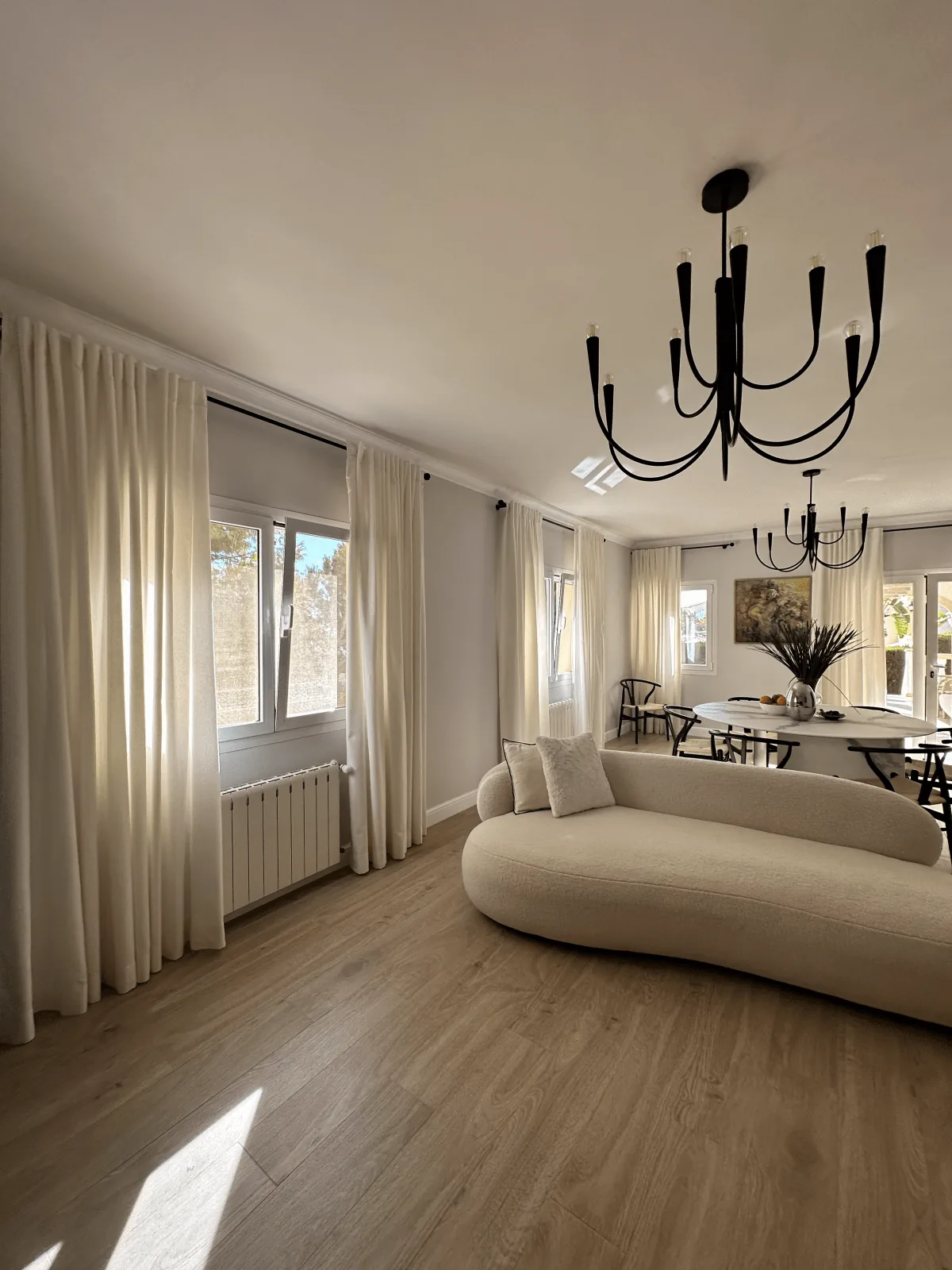 Salón de un chalet con visillo a medida y sofá curvo