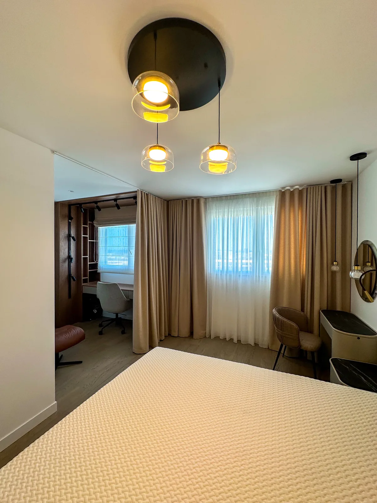 Dormitorio con cortina y visillo a medida y lámpara de diseño