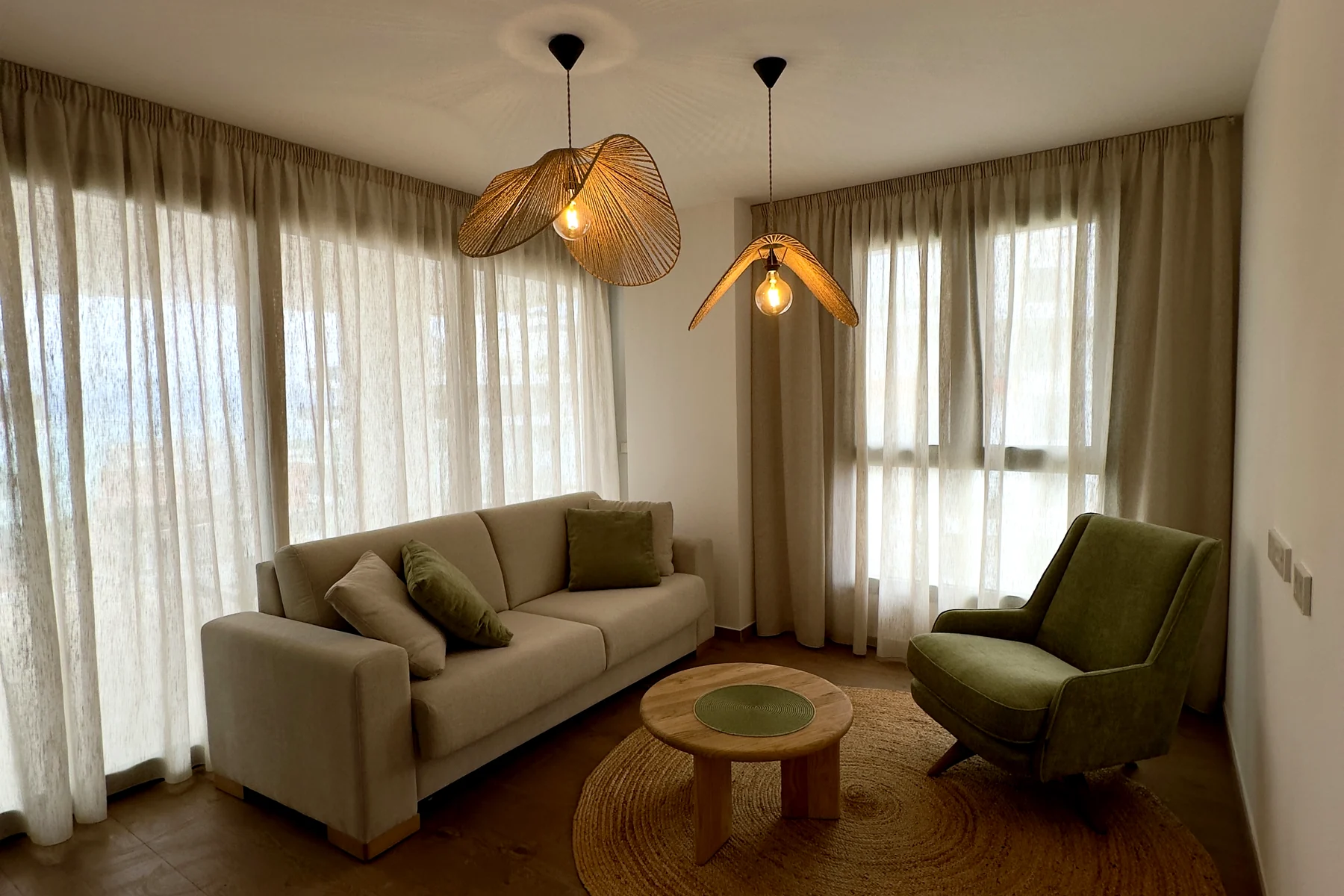 Salón con cortinas camel y visillo en dos ventanas contiguas