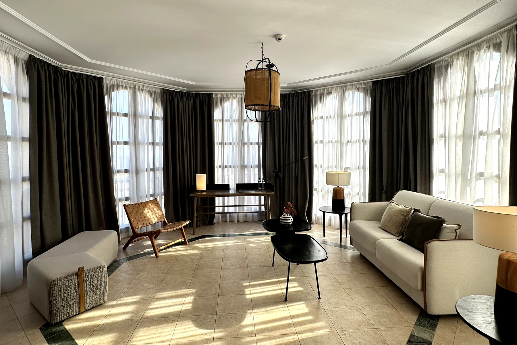 Salón con cortina gris oscuro y visillo, con la luz marcada sobre el mármol