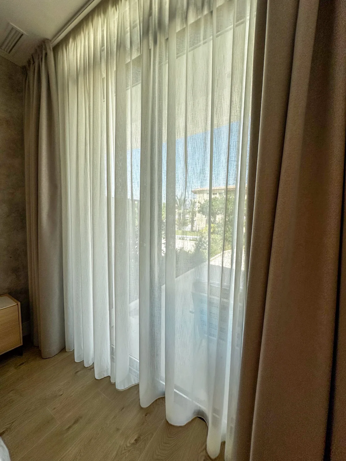 Visillo de onda perfecta combinado con cortina beige en un ventanal